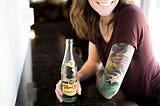 A woman with tattoos drinking a sparkling water
