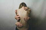 A woman with hands all over her naked back