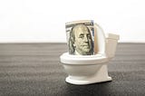 A 50-dollar bill being flushed down a small toilet