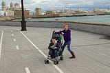 A young girl pushes her 5-year-old brother in a stroller in the waterfront area of Cadiz, Spain.