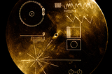 Upscaled image of NASA’s Voyager Golden Record cover, showing a circular gold disc engraved with symbolic diagrams for playback, image decoding, a pulsar map, and a hydrogen atom reference, set against a black background.