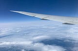 The view out the window of the plane flying above the clouds