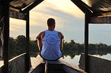 Man sitting alone on a boat gazing into a sunset