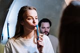 A woman with a toothbrush staring in the mirror