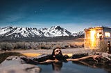 Man relaxes in hot springs with beautiful snowy mountains in the background