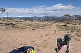 daytime scene overlooking the Colorado mountains with shoes and a backpack in frame