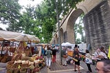 A lively French market underneath an acqueduct.