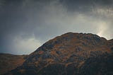 A mountain top with dark grey skies overhead.