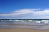 picture of beach with waves and blue sky