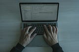 Laptop on a wooden desk while programming