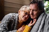 Portrait of senior couple sitting in the evening on terrace, hugging.