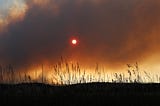 The sun sets behind wildfire smoke from the Alexander Mountain fire in Loveland, Colorado.