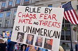 A protester holds up a handmade sign, “Rule By Chaos, Fear, Hate, and Threats is UNAMERICAN.” Photos below this are of Adolph Hitler, Donald Trump, Vladimir Putin, and Xi Jinping. (Photo by author.)