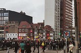 Picture of a protesting crowd, six Colombian flags are being waved by protesters.