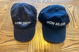 Photo of two baeball caps, Dow 20,000 and Dow 40,000