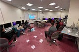 Students in a computer lab classroom watching a video presentation on deceptive patterns. (faces blurred for privacy)