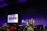 A dark purple stage, a slide that says SIGCSE, and the organizing committee kicking things off.