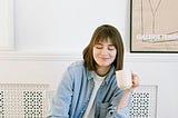 Woman sitting at a laptop with a beverage in hand and smiling