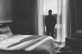 Man looking out window of hotel room