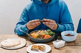 Man eating delicious meat at table. What happens when you follow Tim Ferris’s Slow Carb Diet? What is the slow-carb diet? How to do the slow-carb diet?