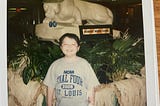A young boy smiling with a Final Four St. Louis t-shirt on.