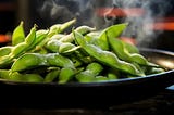 Steamed edamame pods on a ceramic plate