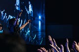 A woman in a concert with crowd lifting hands