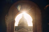 An image of L’Hôtel des Invalides in Paris, with a solar flare peeking through an archway