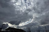 A photo of a cloudy sky, with a long arc of cloud break showing blue sky above.