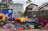 The final mural, with the sparrow in the lower right corner, viewed from behind the railing on the sidewalk.