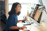 A woman sitting at an office desk using her computer.