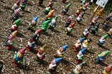 A disconcerting number of gnomes on a dirt field.