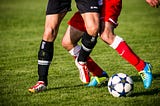 THe legs of two soccer players battling for the ball.