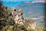 View of the valley in the blue mountains in Australia with the three sisters rock formation in the foreground.
