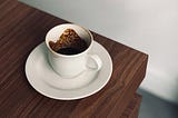 Dirty white coffee cup with a saucer on a wooden table