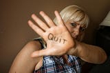 A woman with her hand up and quit written on her palm.