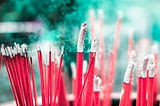 Bright red incense sticks smoking away, with ashen gray tips