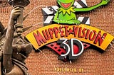 The Muppet Vision 3D sign on the show’s facade, foregrounded by a fountain of Ms. Piggy dressed as the statue of liberty.