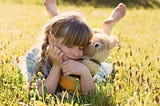 Girl snuggling with teddy bear on a meadow with yellow flowers