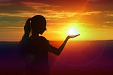 Picture of a girl seemingly holding the sun in her hand.