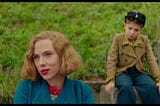 Rosie (Scarlett Johansson) and Jojo (Roman Griffin Davis) in the same shot, while the former sits in the front, and the latter sits behind