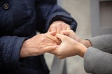 Older person holding hands with younger person