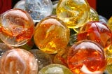 a group of orange, yellow, and blue colored glass marbles