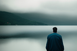 A depressed guy sitting near a lake