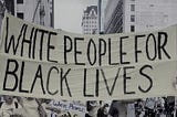 Image of people carrying a yellow banner that says “White People 4 Black Lives” in black writing.