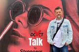The author Stefan Thomas in front of a banner with the words Talk to Strangers behind him.