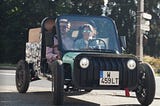 Two people taking their Kilow La Bagnole electric vehicle for a city drive.