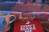 Book on coffee table with cup of tea against brick wall