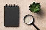 A notebook, a magnifying glass and a succulent on top of a Braille textured sheet. (Freepik)