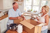 Seniors couple packing boxes in their kitchen.